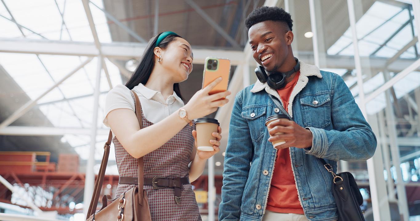 Zwei lächelnde Schüler, die auf ein Smartphone schauen und damit die Sprachlernlösungen von Rosetta Stone für Schulen symbolisieren, die interaktives und mobiles Lernen fördern.